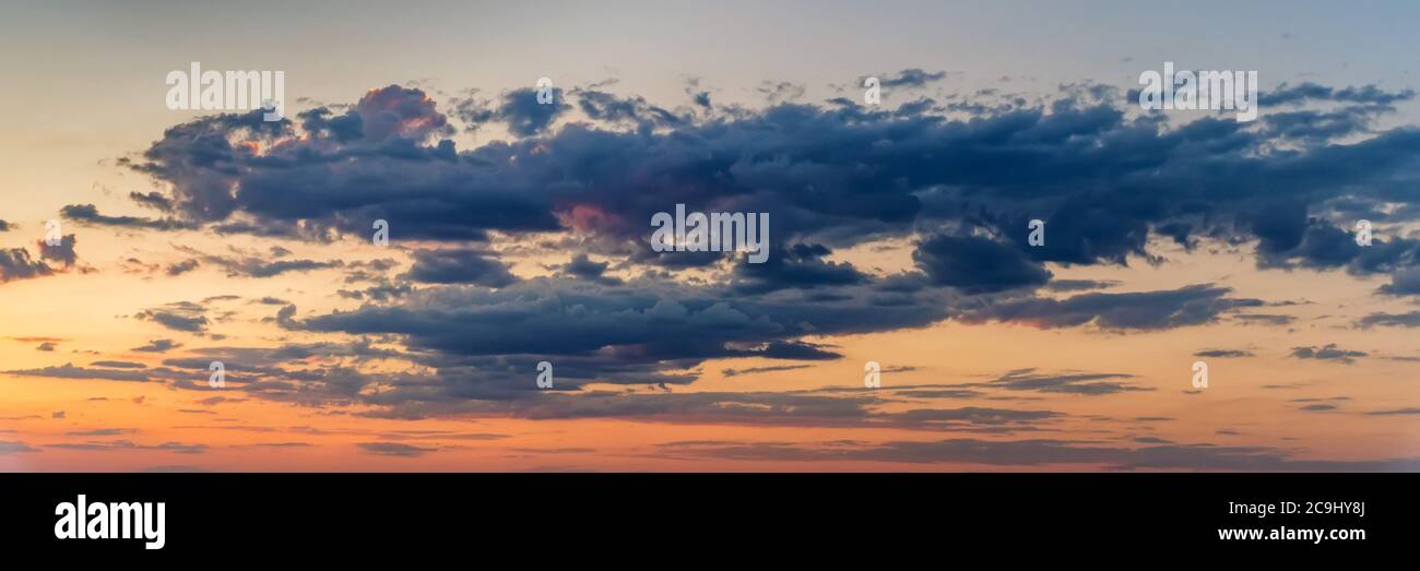 Dramatic panoramic skyscape with dark stormy clouds during sunrise Stock Photo