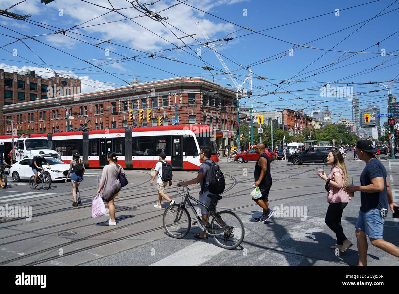 Toronto, Canada - July 31, 2020: Pedestrians and cyclists cross at the busy corner of Queen and Spadina streets. Stock Photo