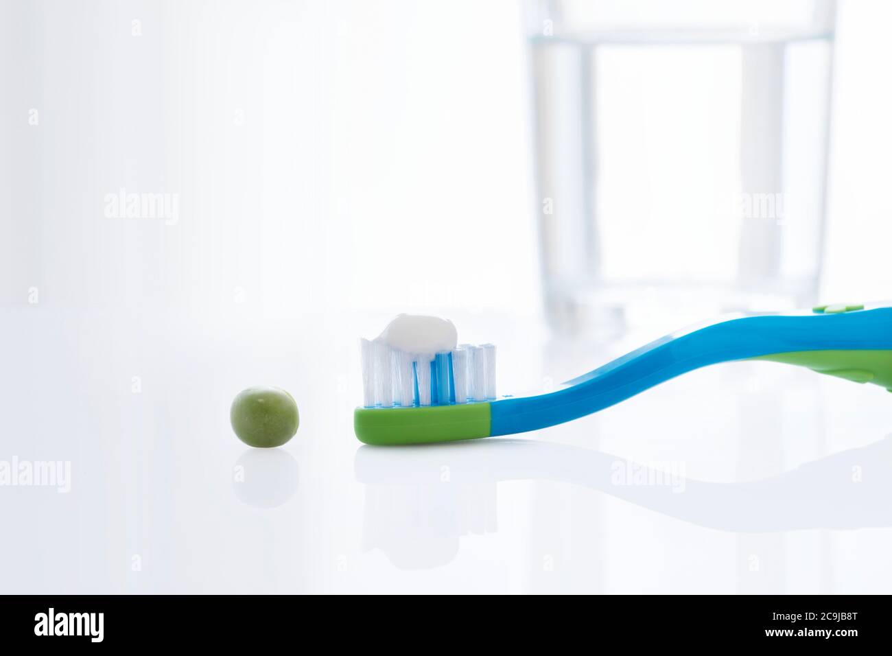 Toothbrush with a pea sized amount of toothpaste against a white background. Stock Photo
