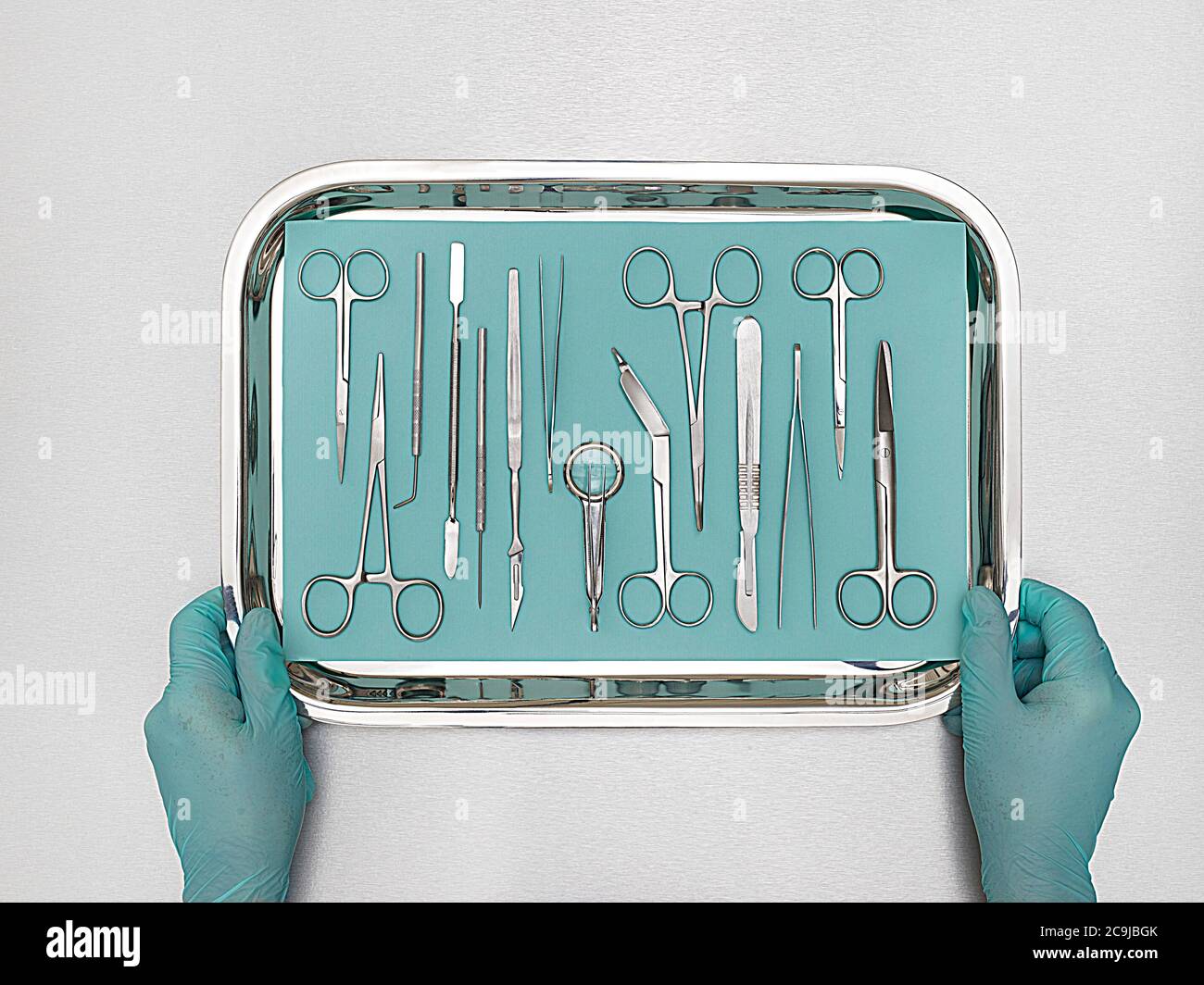 Person holding tray with surgical equipment against a white background. Stock Photo