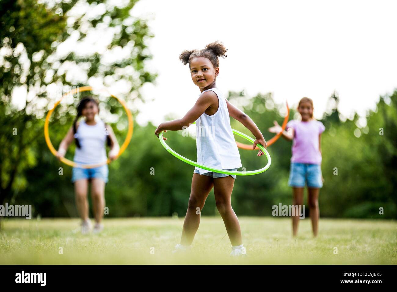 Girls playing with hula hoops in park. Stock Photo