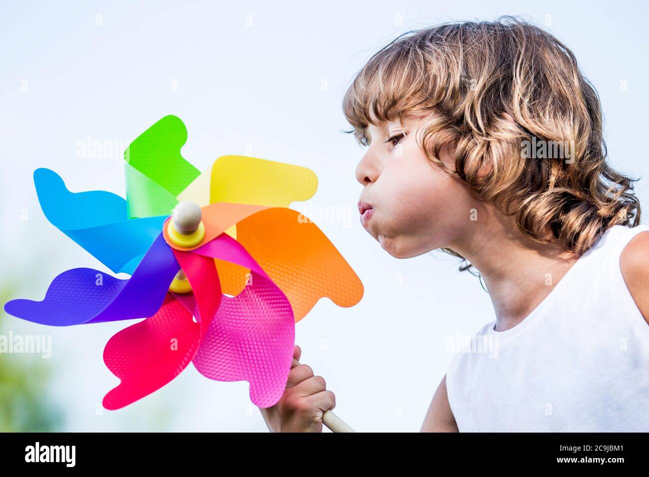Boy blowing colourful paper windmill in park. Stock Photo