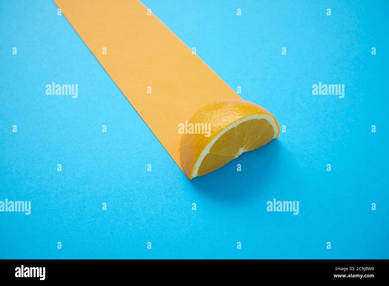 Lemon half and yellow stripe against a blue background. Stock Photo