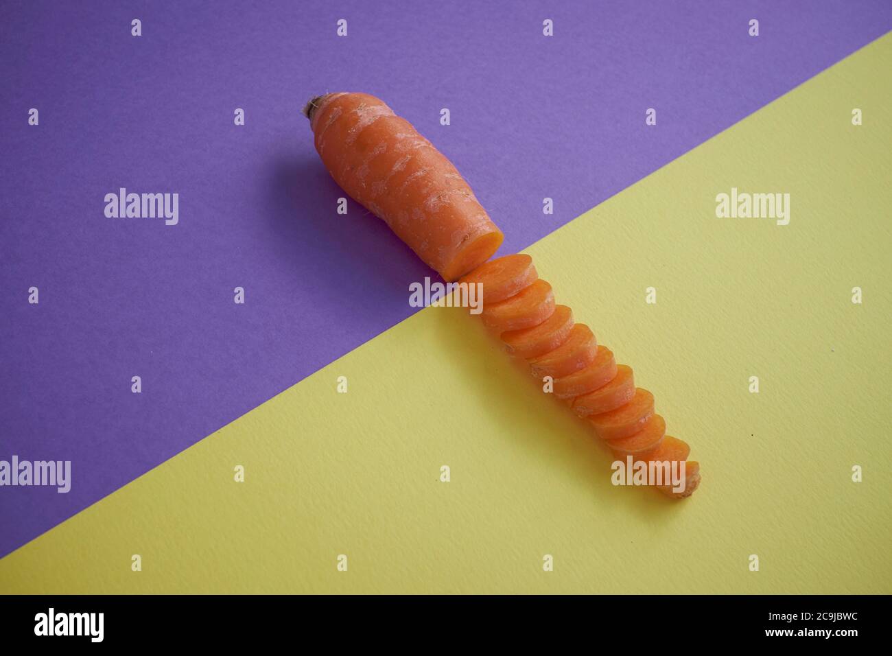 Carrot against a purple and yellow background. Stock Photo
