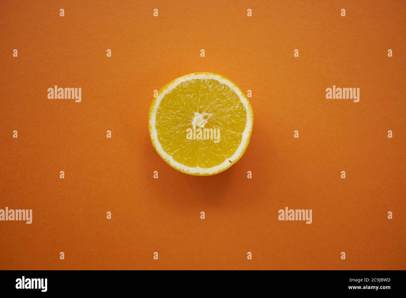 Lemon half against an orange background. Stock Photo