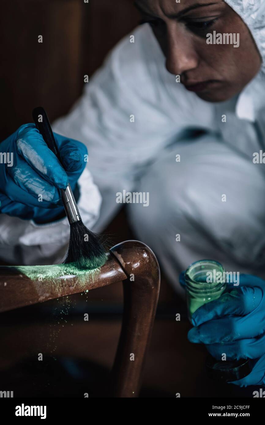 Crime scene. Forensics expert dusting for fingerprints at a crime scene