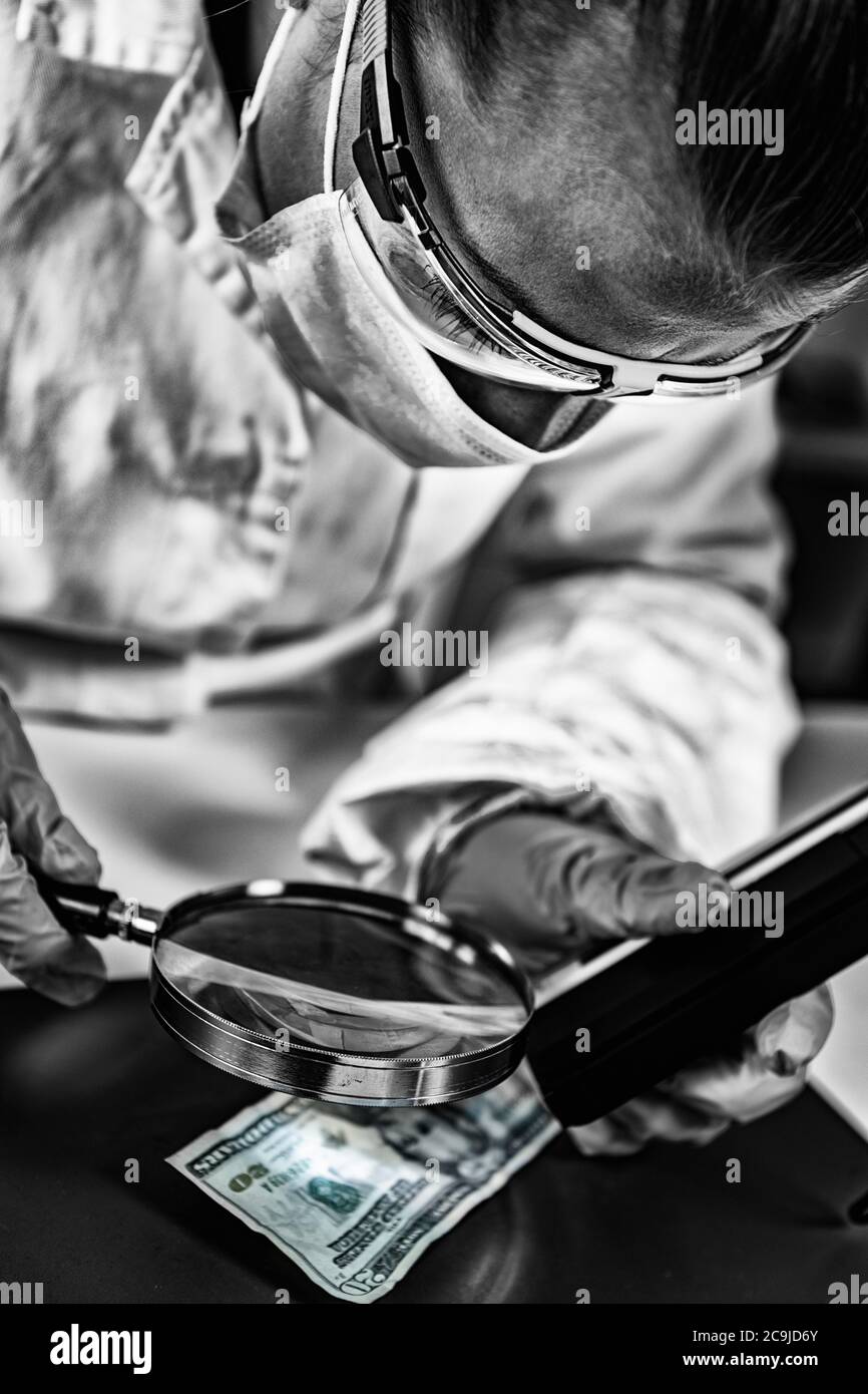Forensics. Forensic science expert examining banknote with magnifying