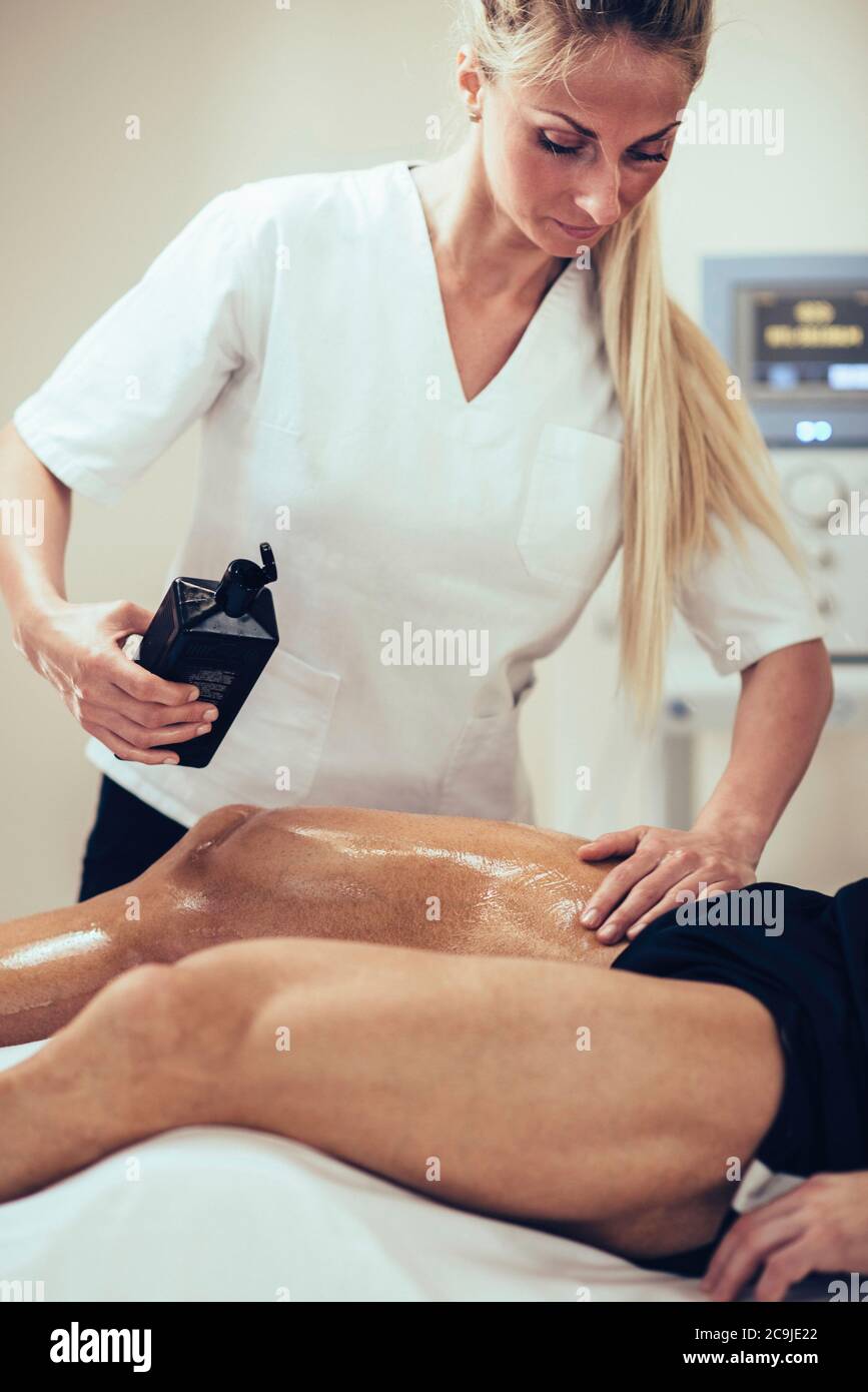 Sports massage. Physical therapist massaging man, applying massage oil  Stock Photo - Alamy