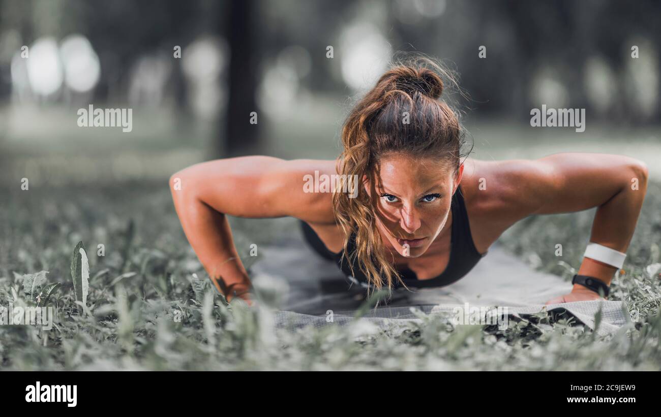 Female athlete doing push-ups outdoors. Stock Photo