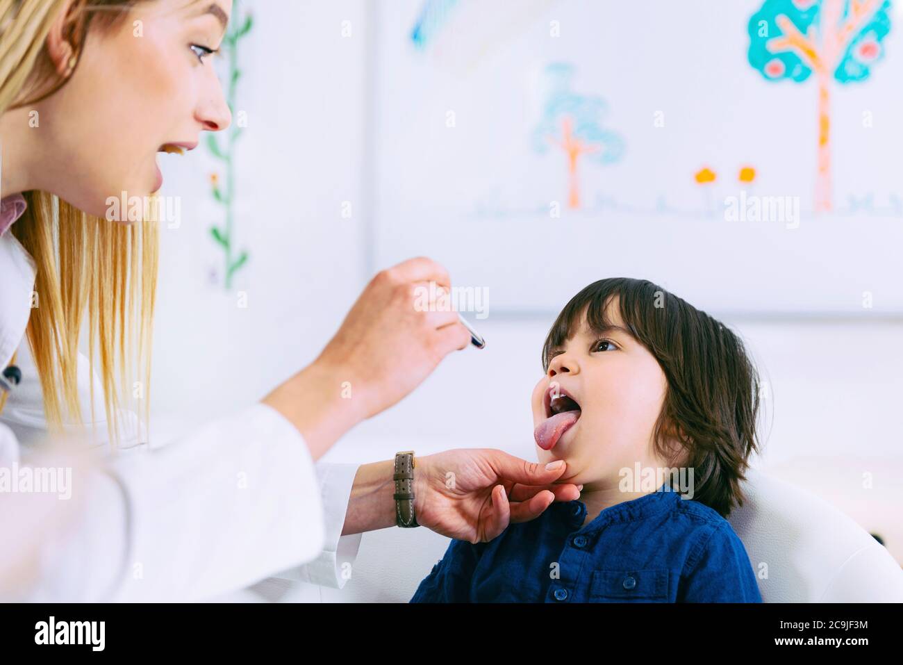 Paediatrician examining boy's throat with pen torch Stock Photo Alamy