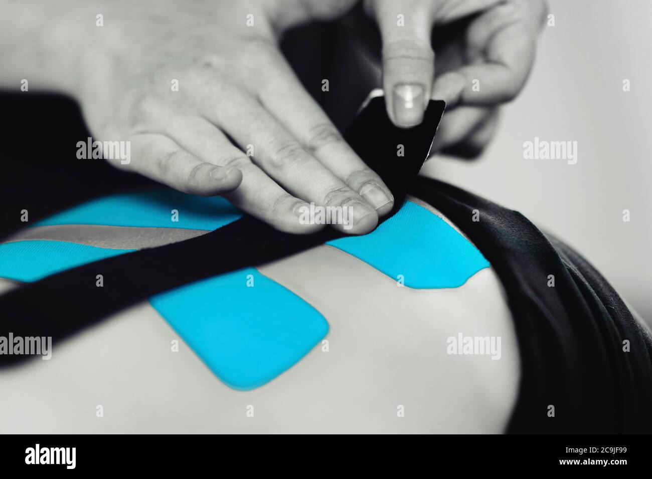 Physical therapist placing kinesio tape on patient's back. Stock Photo