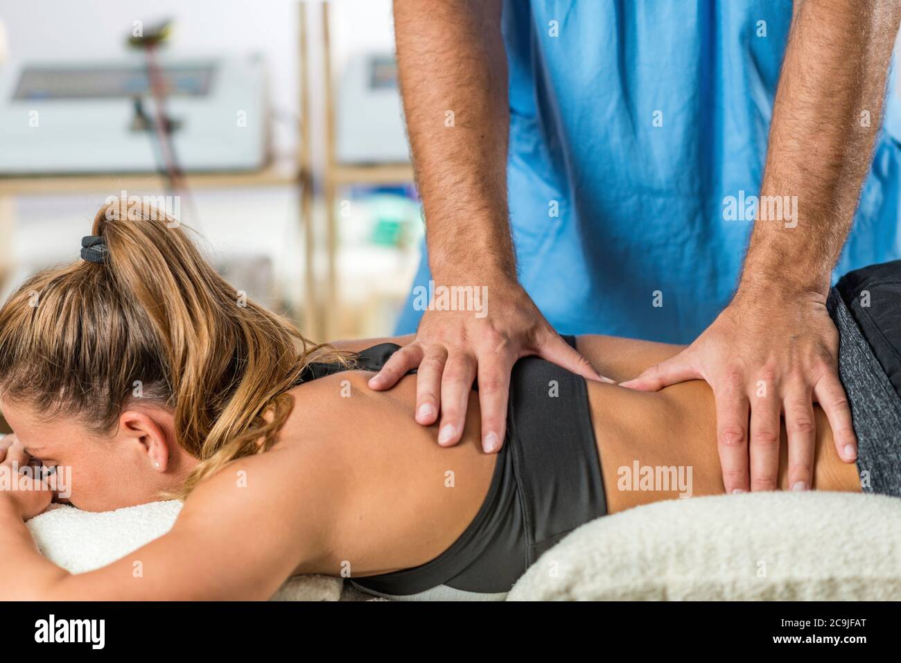 Physical therapy. Therapist applying strong pressure onto lower back muscles. Stock Photo