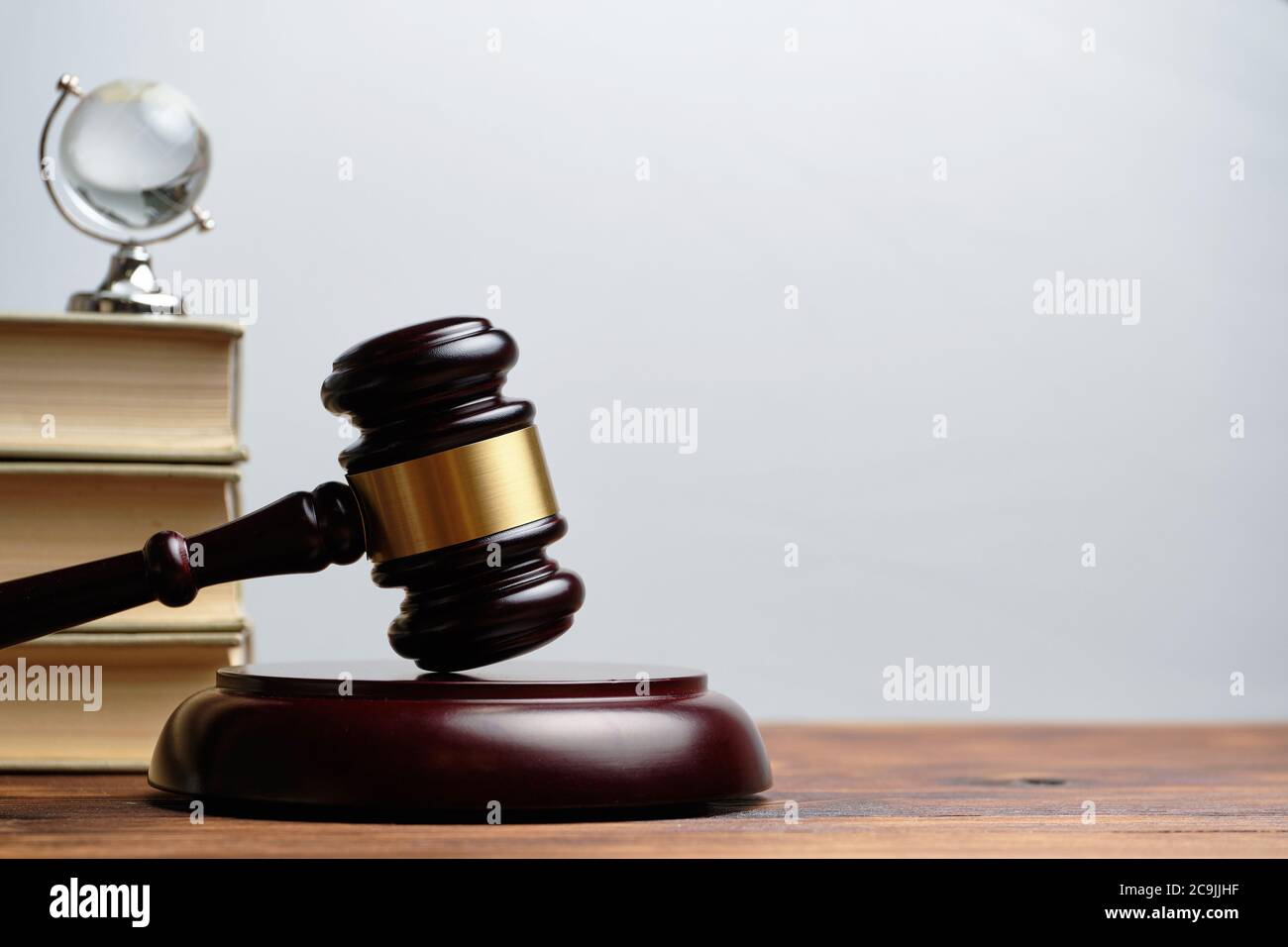 Judge hammer with books and small glass globe on white background. Stock Photo
