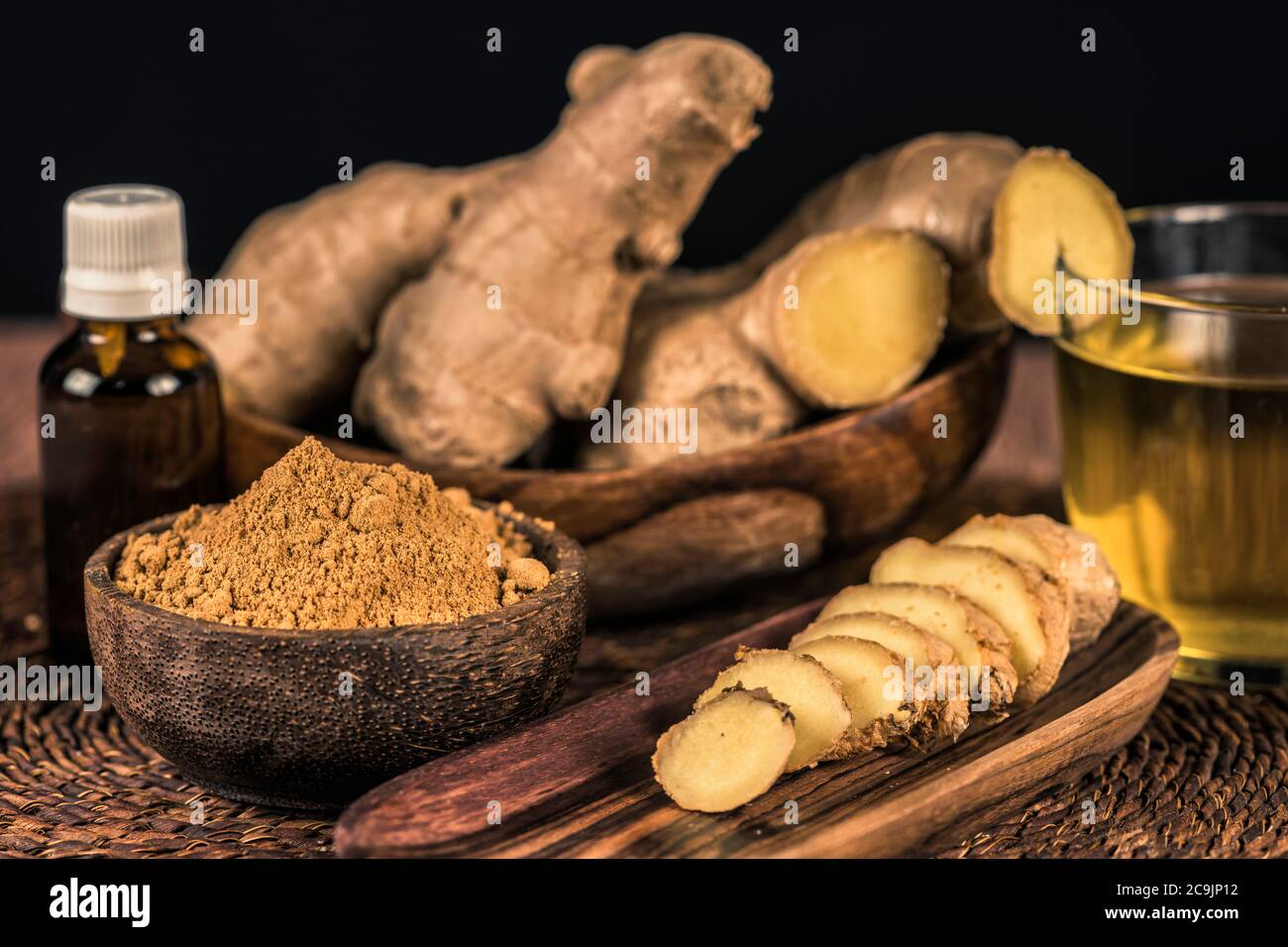 Sliced ginger root and ginger powder in the bowl on the table. Anti