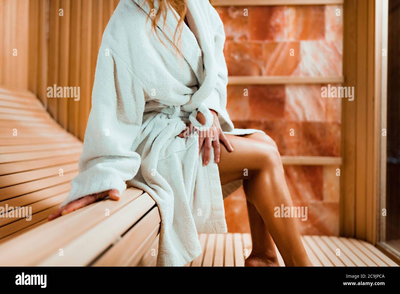 Woman relaxing in salt room. Sitting in bathrobe and enjoying. Stock Photo