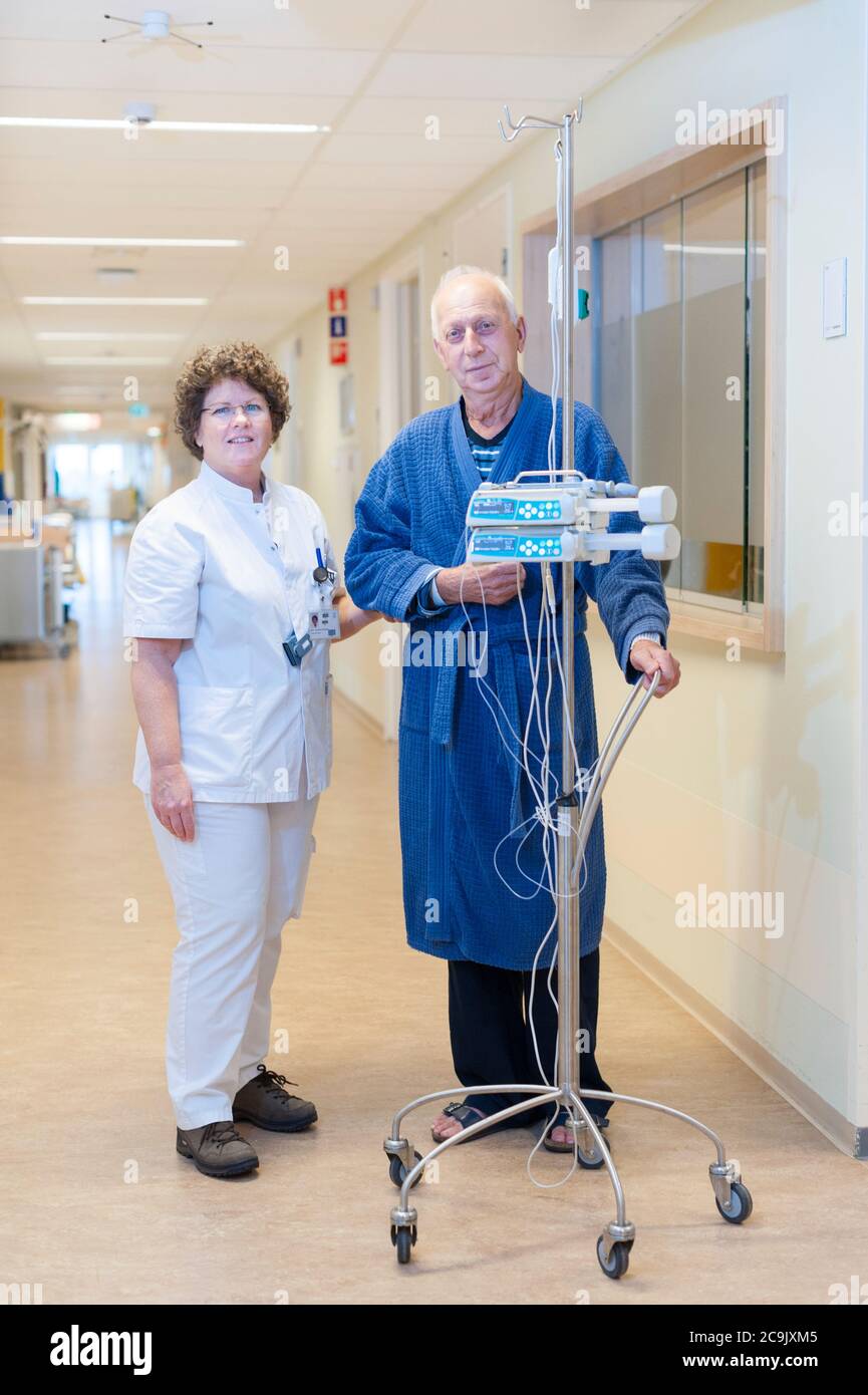 Nurse and patient walking through the hall with IV pole Stock Photo Alamy