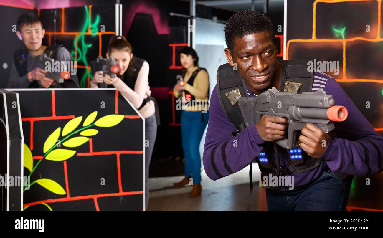 Emotional African man with a his laser pistol playing laser tag with  friends on dark labyrinth Stock Photo - Alamy