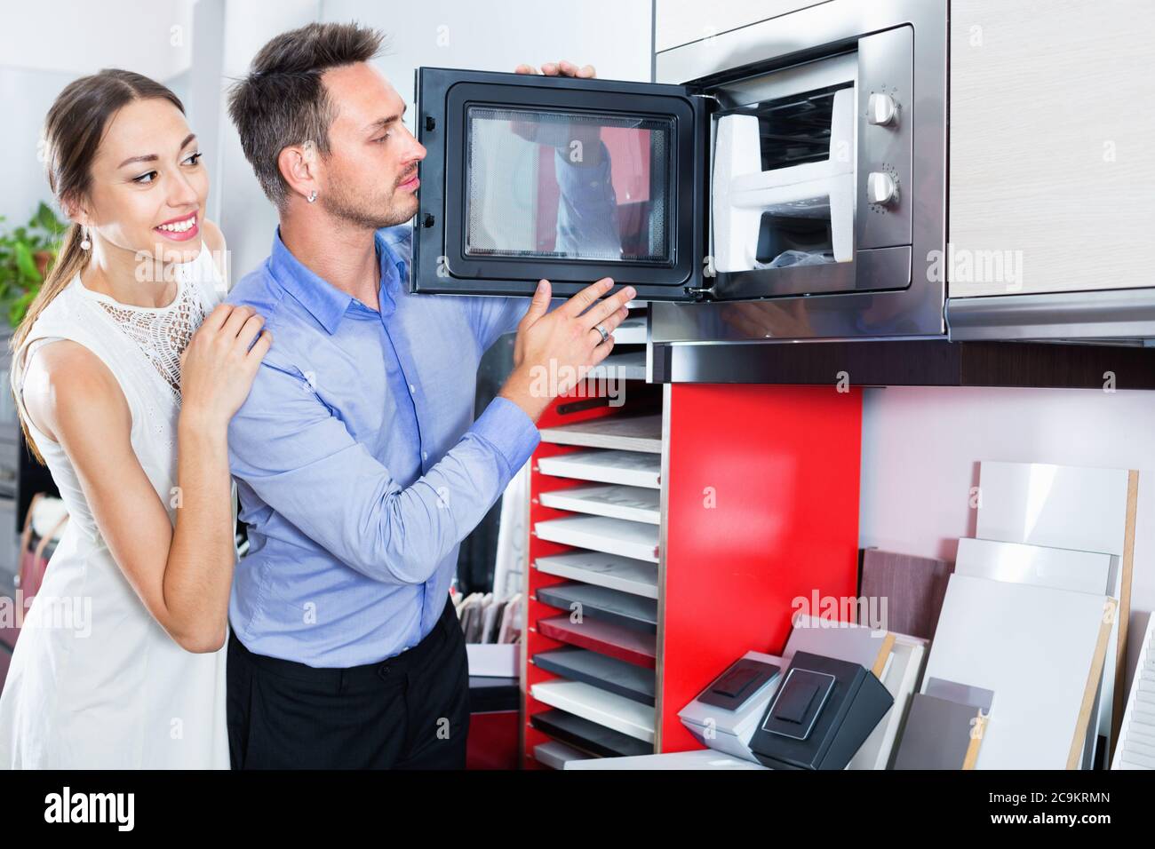 Young happy positive couple choosing microwave in household appliance section in furnishing store Stock Photo