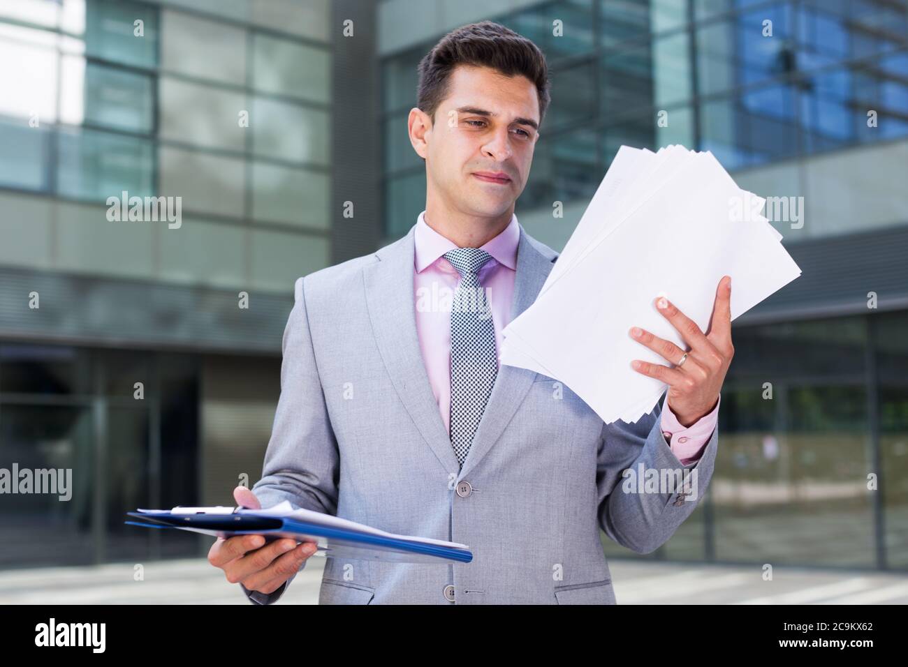 Businessman holding folder with documents and attentively reading Stock Photo