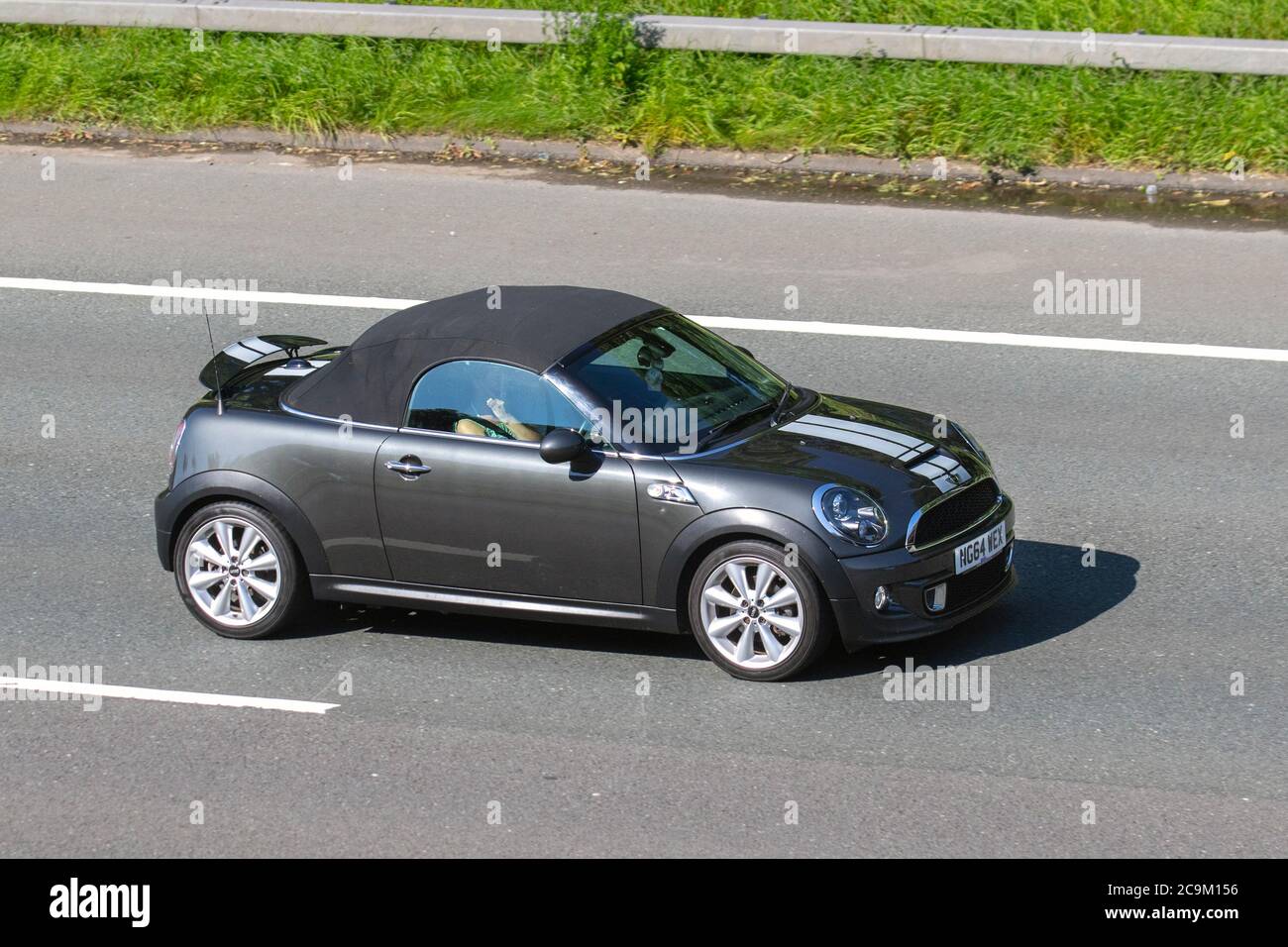 2015 grey white Mini Roadster Cooper SD; Vehicular traffic moving vehicles, cars driving vehicle on UK roads, motors, convertible, convertibles, soft-top, open topped, roadster, cabriolets, drop-tops cars motoring on the M6 motorway highway network. Stock Photo