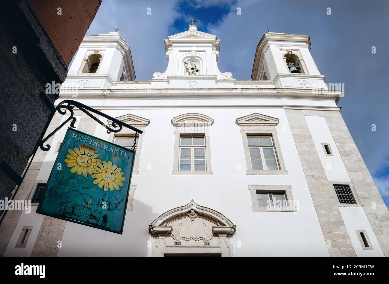 LISBON, PORTUGAL - FEBRUARY 2, 2019: Church of Sao Miguel and sign of a nearby typical restaurant in Alfama, historic district of Lisbon, Portugal, fa Stock Photo