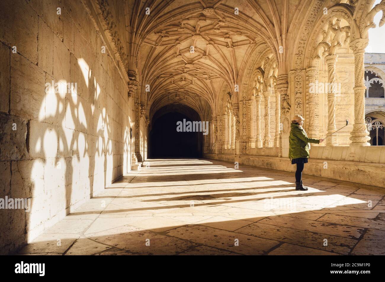 LISBON, PORTUGAL - FEBRUARY 3, 2019: Asian woman making a snapshot to her shadow with selfie stick and phone in the cloister of the Jeronimos monaster Stock Photo