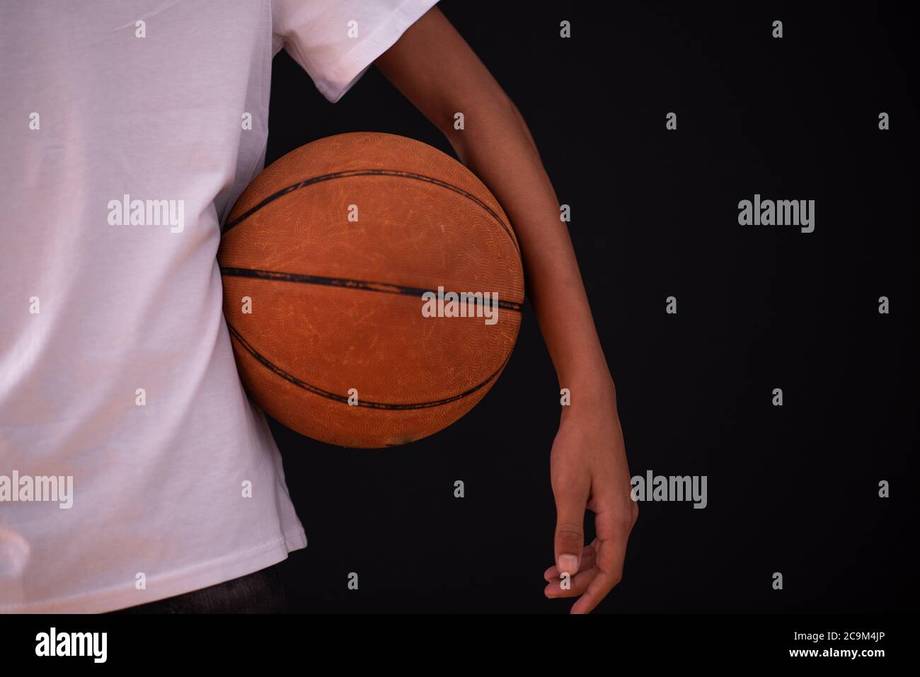 Young person standing with basketball under his arm Stock Photo