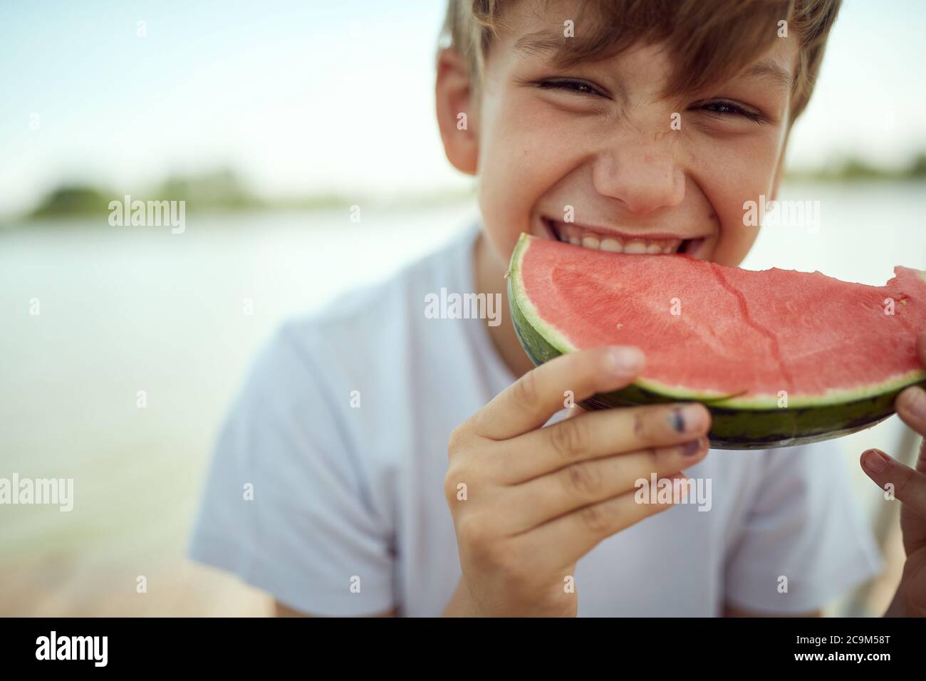 Young boy eating a watermelon on a hot day Stock Photo