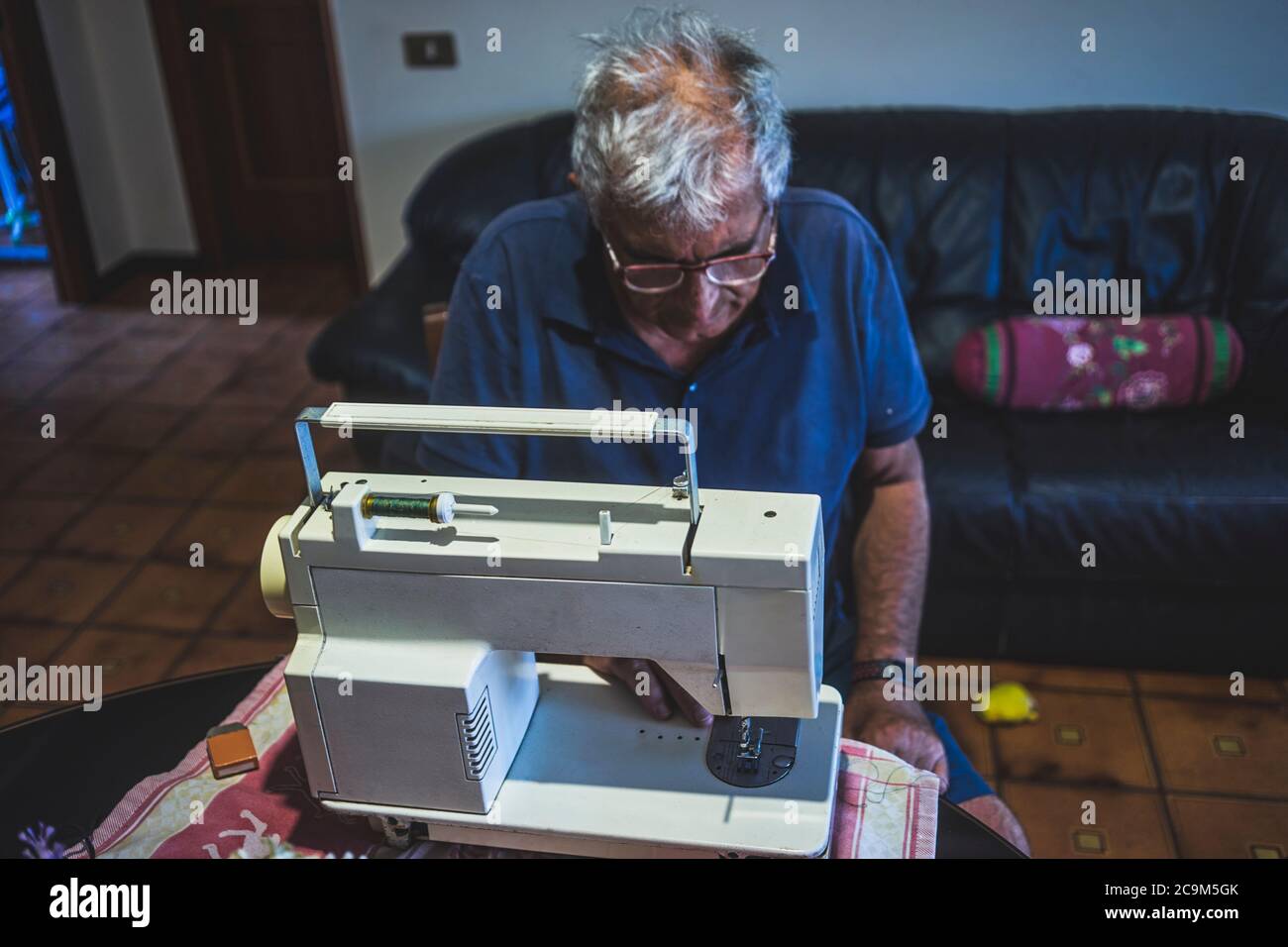 elderly man using a sewing machine Stock Photo