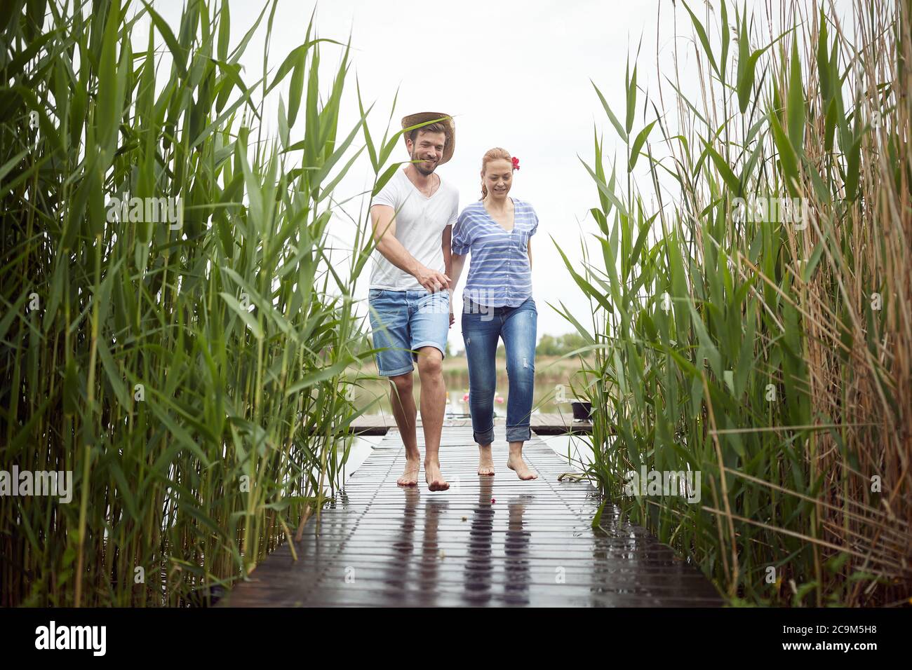 Spouses barefoot walking on a wet dock of the lake Stock Photo