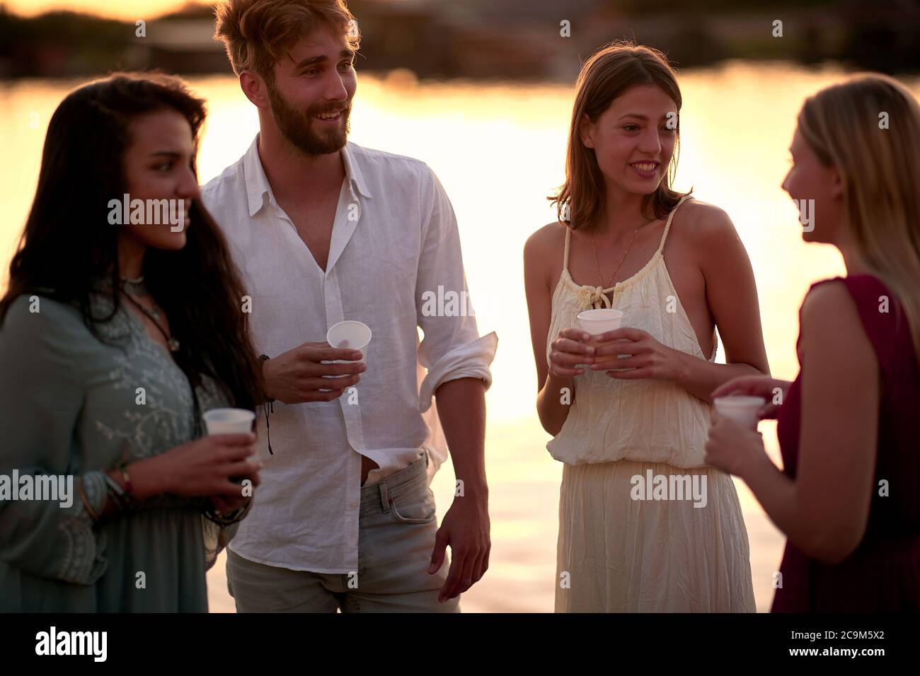 Smiling friends having party at evening - Happy people drinking and having fun. Stock Photo