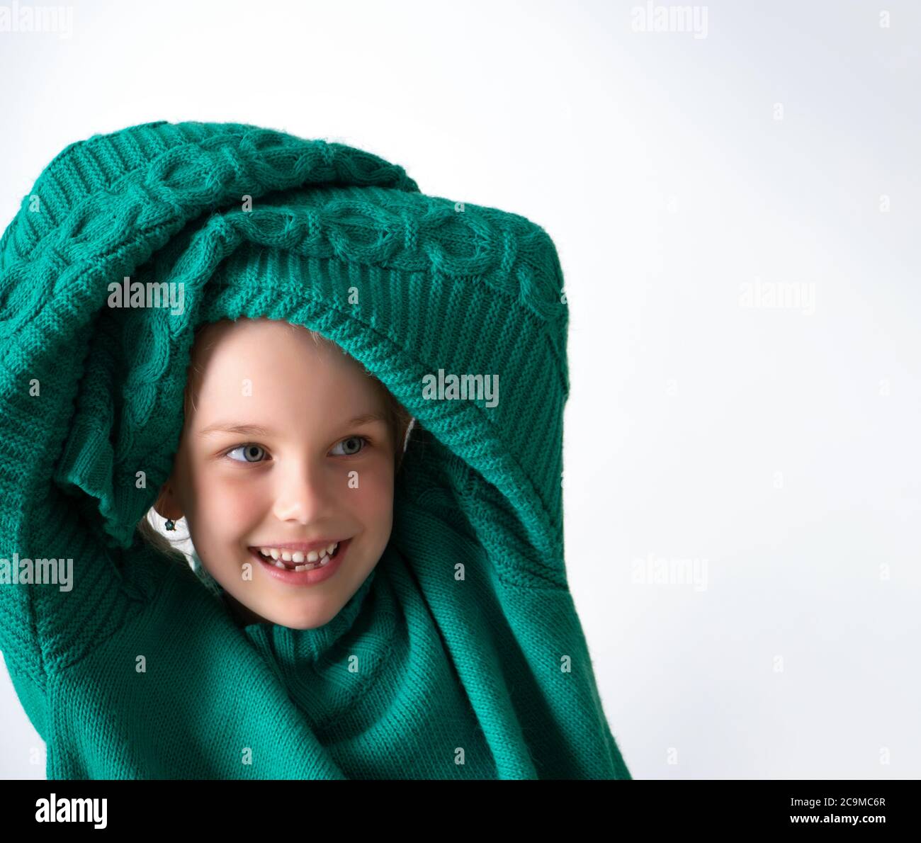 Playful little girl wearing knitted green sweater that is too big for