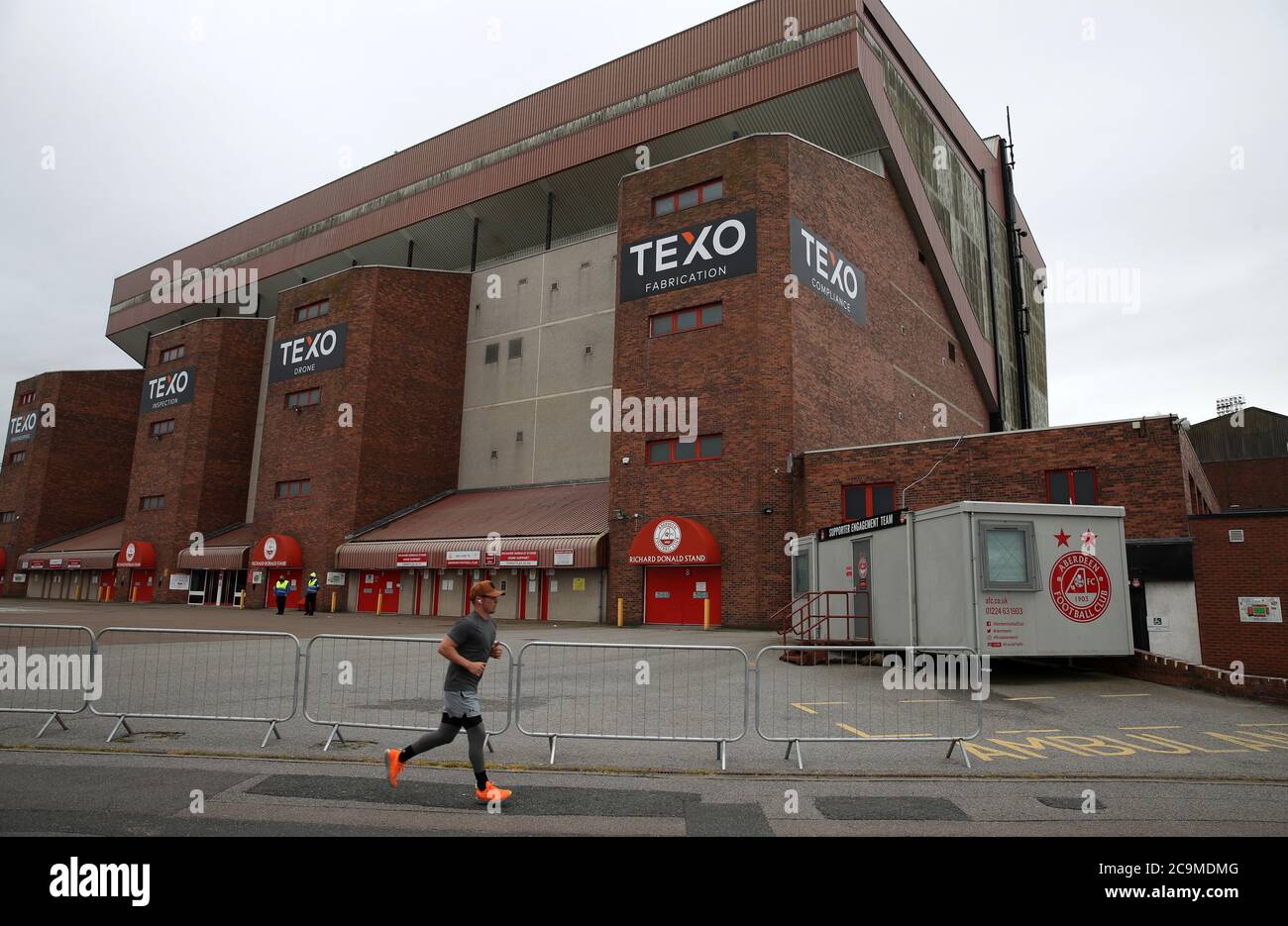 A runners runs past security barriers outside Pittodrie Stadium in Aberdeen, where Aberdeen are due to play Rangers. Stock Photo