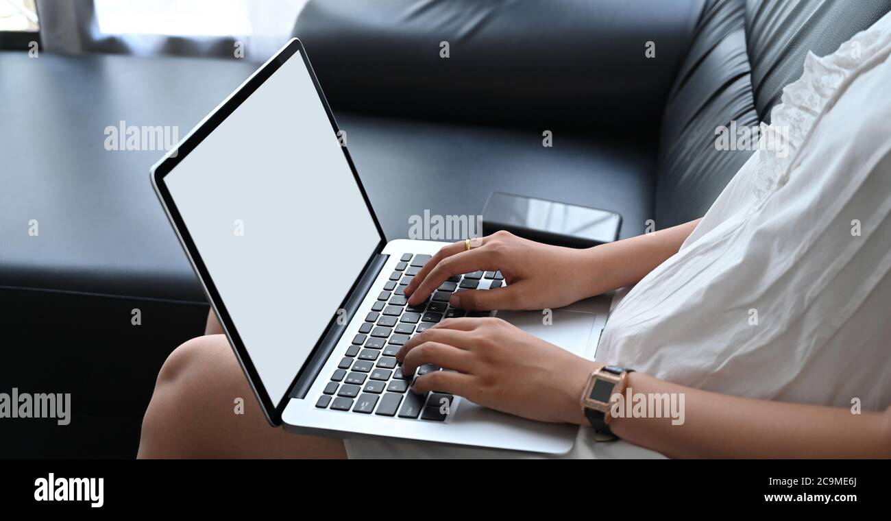 Cropped image of a woman is using a white blank screen laptop while ...