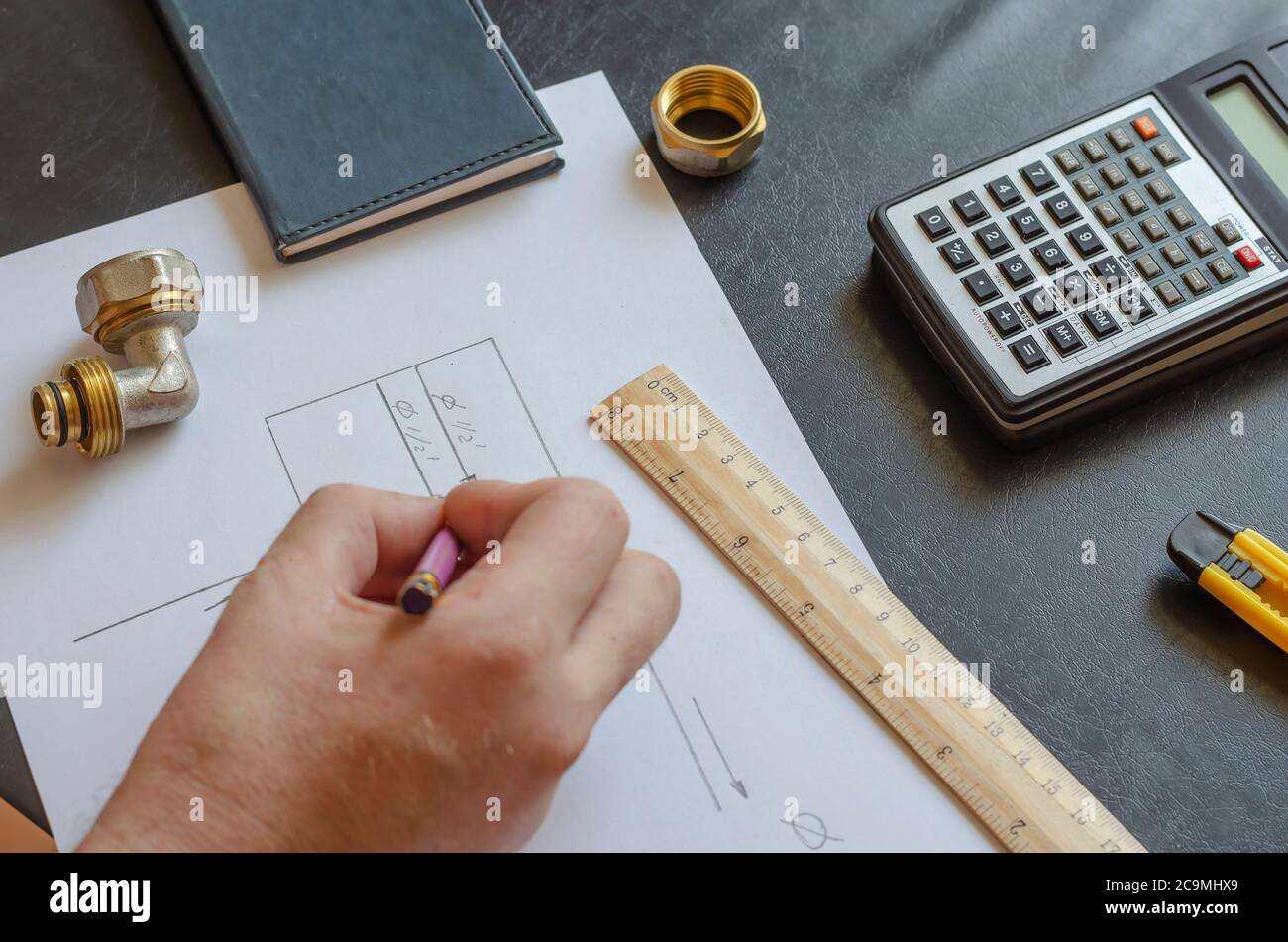 A male hand draws a diagram of home plumbing. Plumber makes the ...