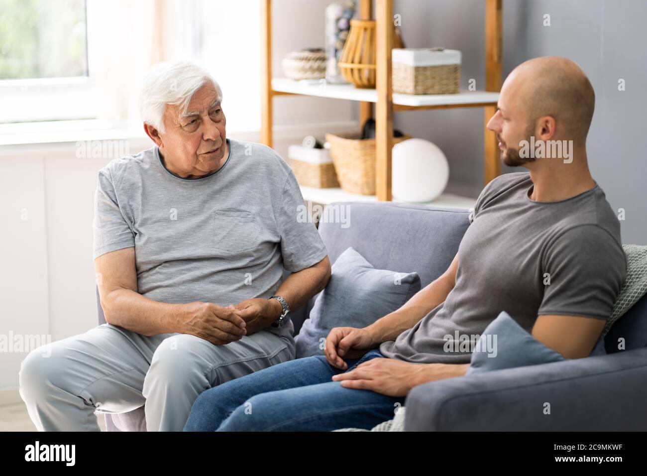 Grandpa Talking To His Grandson In Living Room Stock Photo