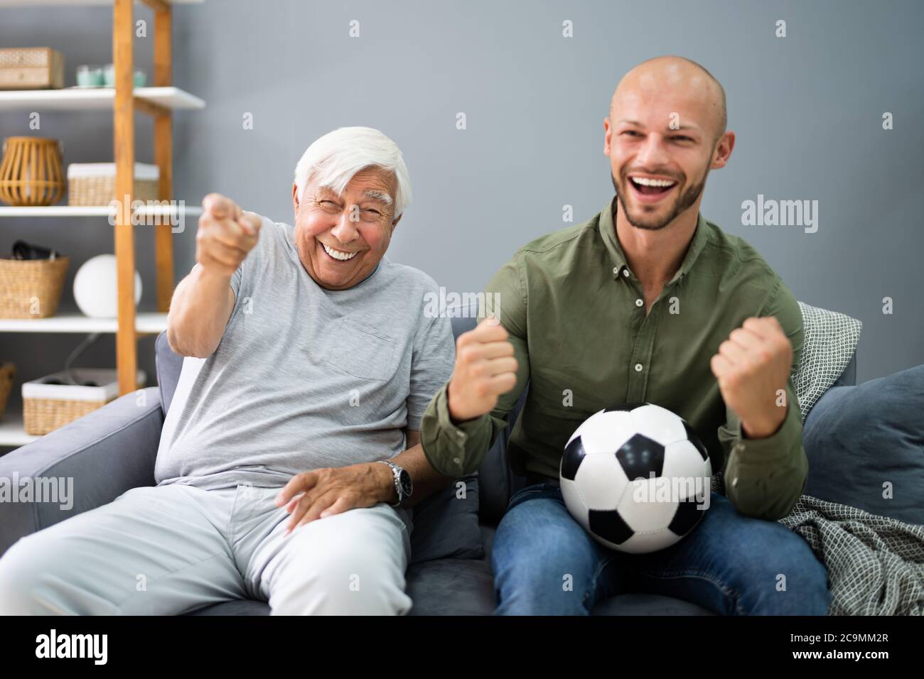 Grandpa And Grandson Watching Football Sport Match On TV Stock Photo