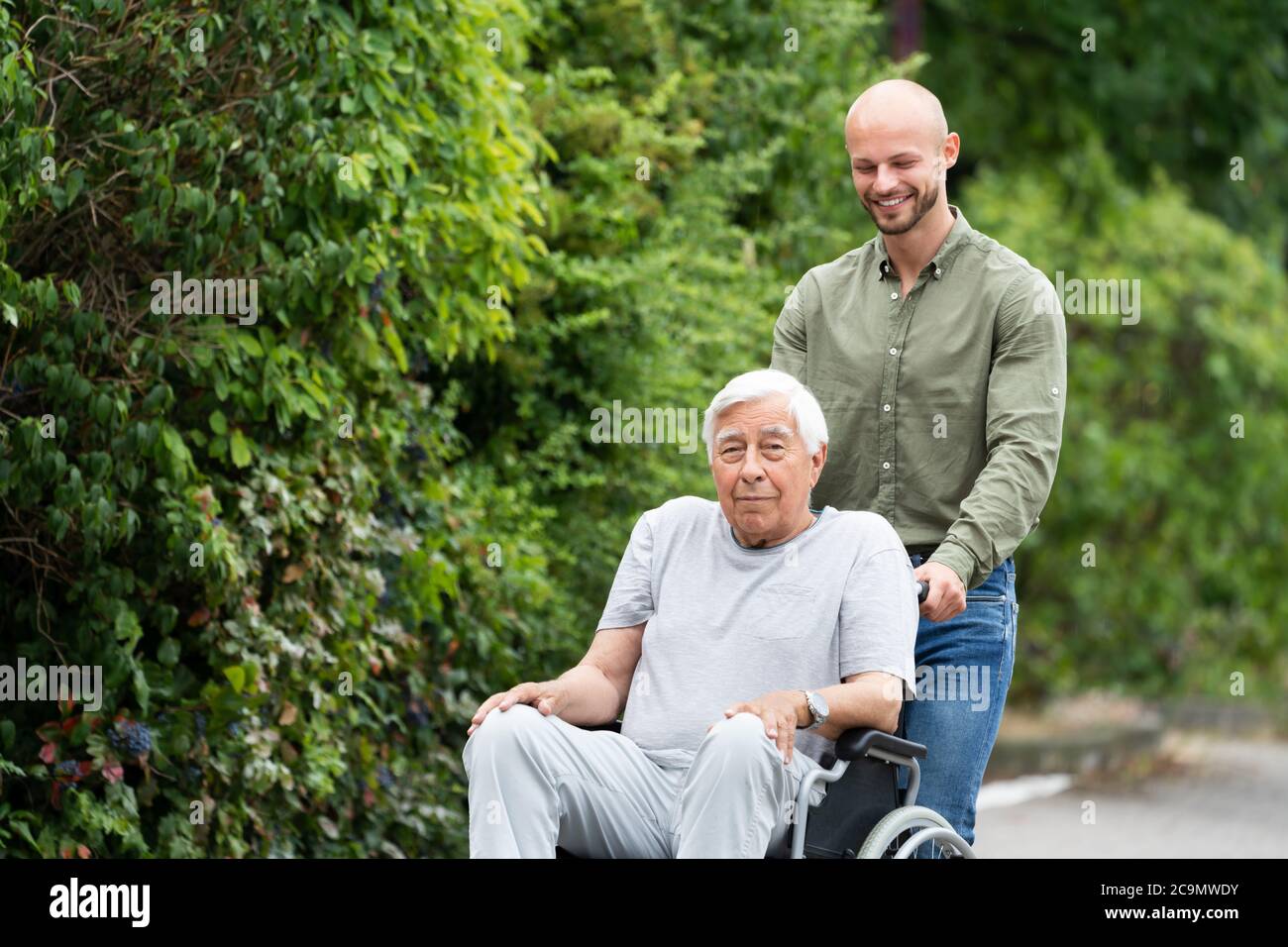 Old Smiling Senior Wheelchair Transport In Park Stock Photo