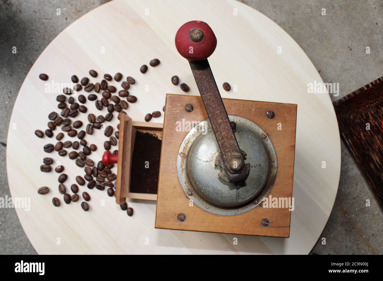 Antique German coffee grinder with grounds in its drawer, and beans