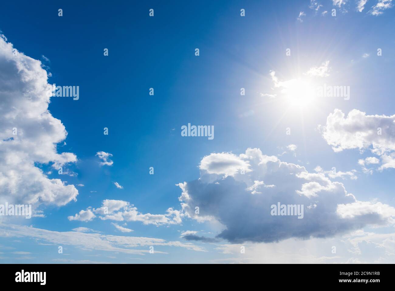 Sun shining in a blue sky with white clouds in the springtime Stock ...