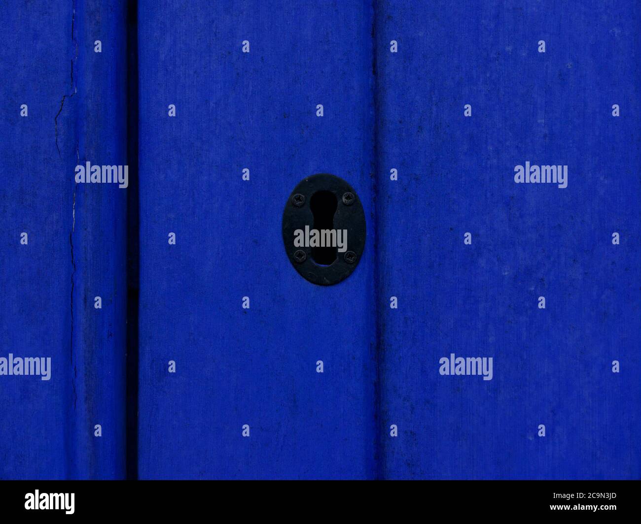 Black keyhole on bright blue wooden panelled door with copyspace Stock Photo