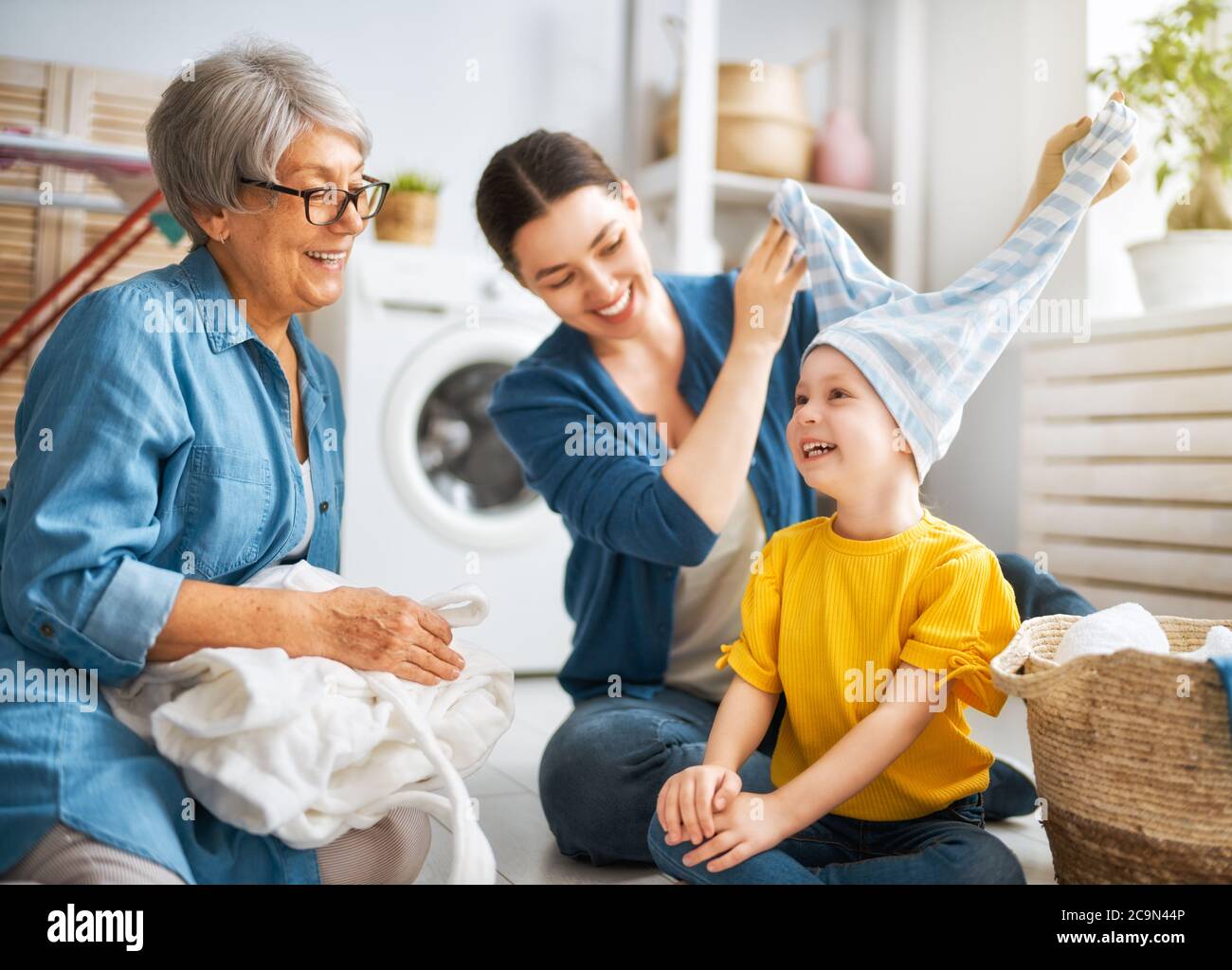grandma, mom and child are doing laundry at home. three generations of family Stock Photo