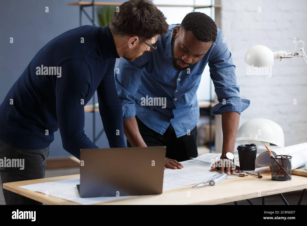 Multiracial engineer team working in office with blue prints and ...