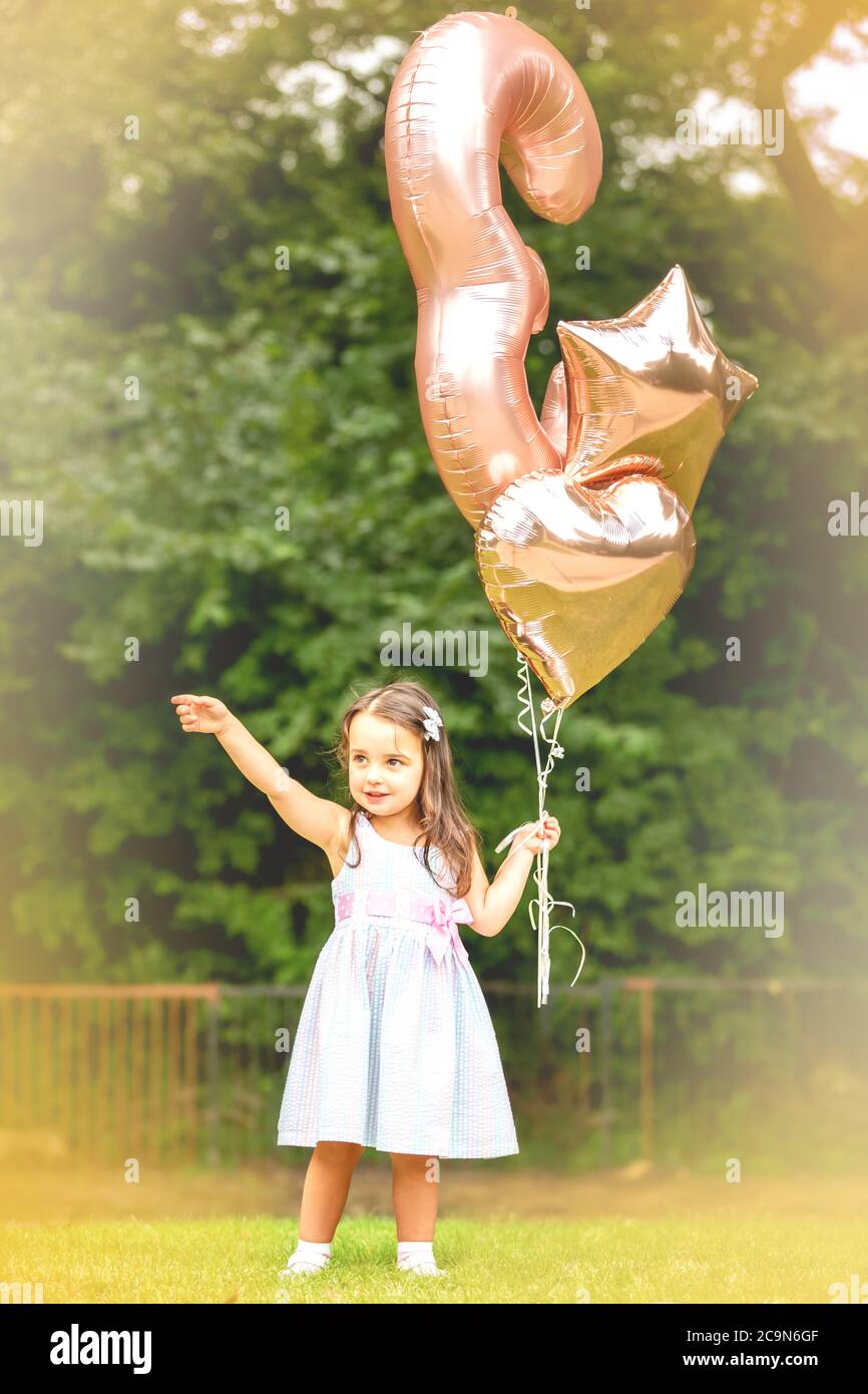 3-year-old birthday girl with her balloons outdoors Stock Photo