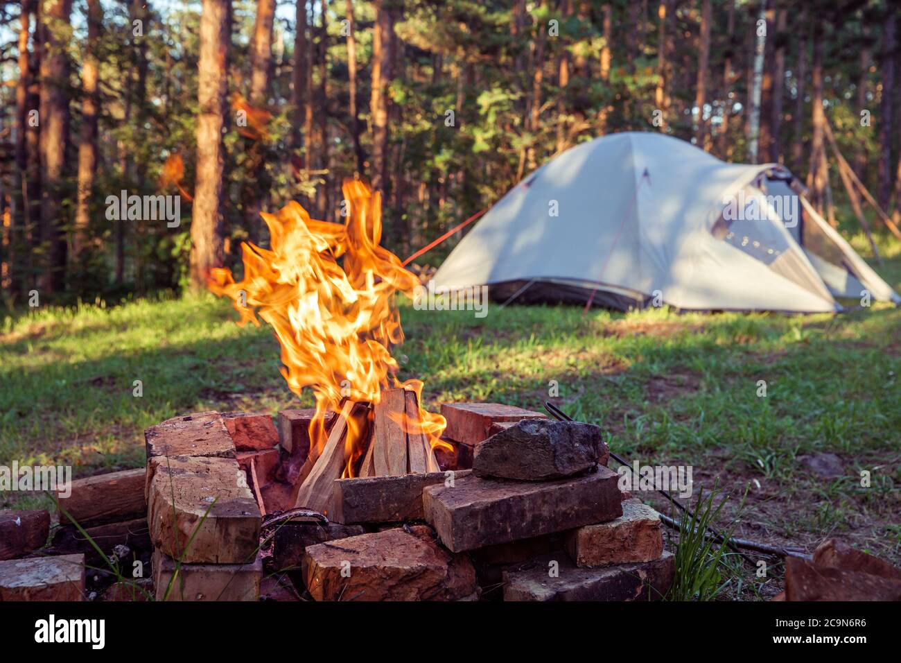 Burning campfire, with camping tent in the background, deep inside the  forest, at sunset Stock Photo - Alamy