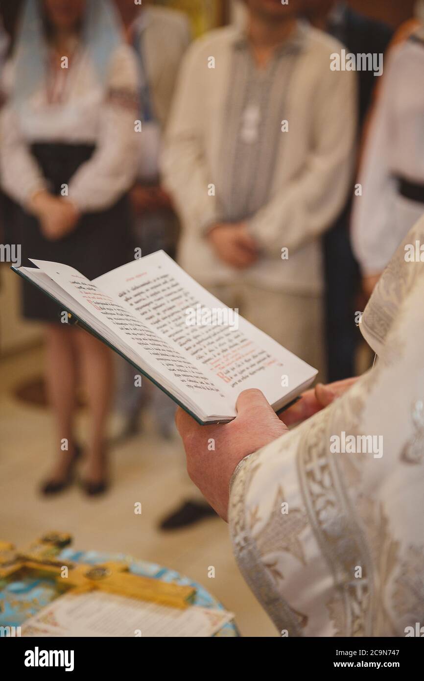 Christening in the church, priest is reading a prayer from the Bible