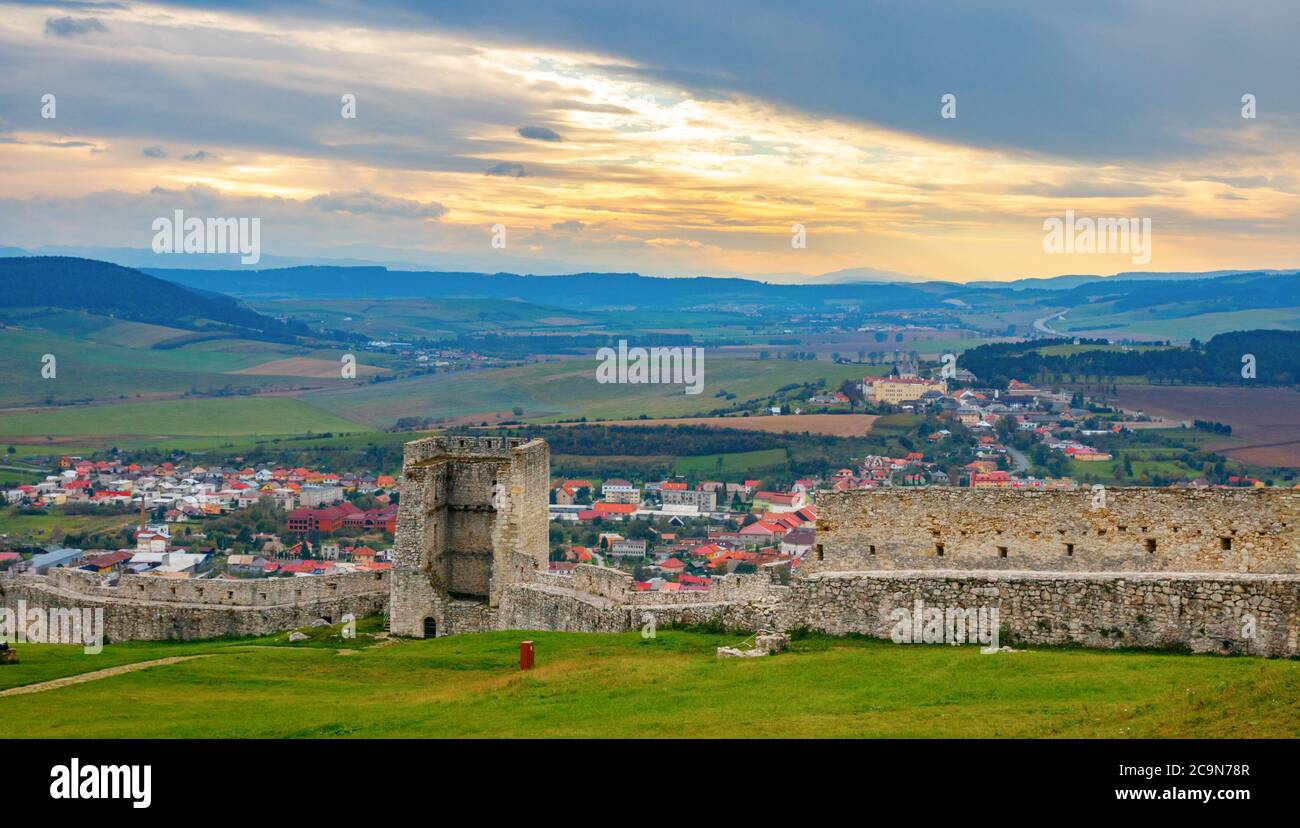Tower and walls of the of Spis Castle ruins and the Spišské Podhradie town in the background on a cloudy afternoon. Spisska Nova Ves, Slovakia. Stock Photo