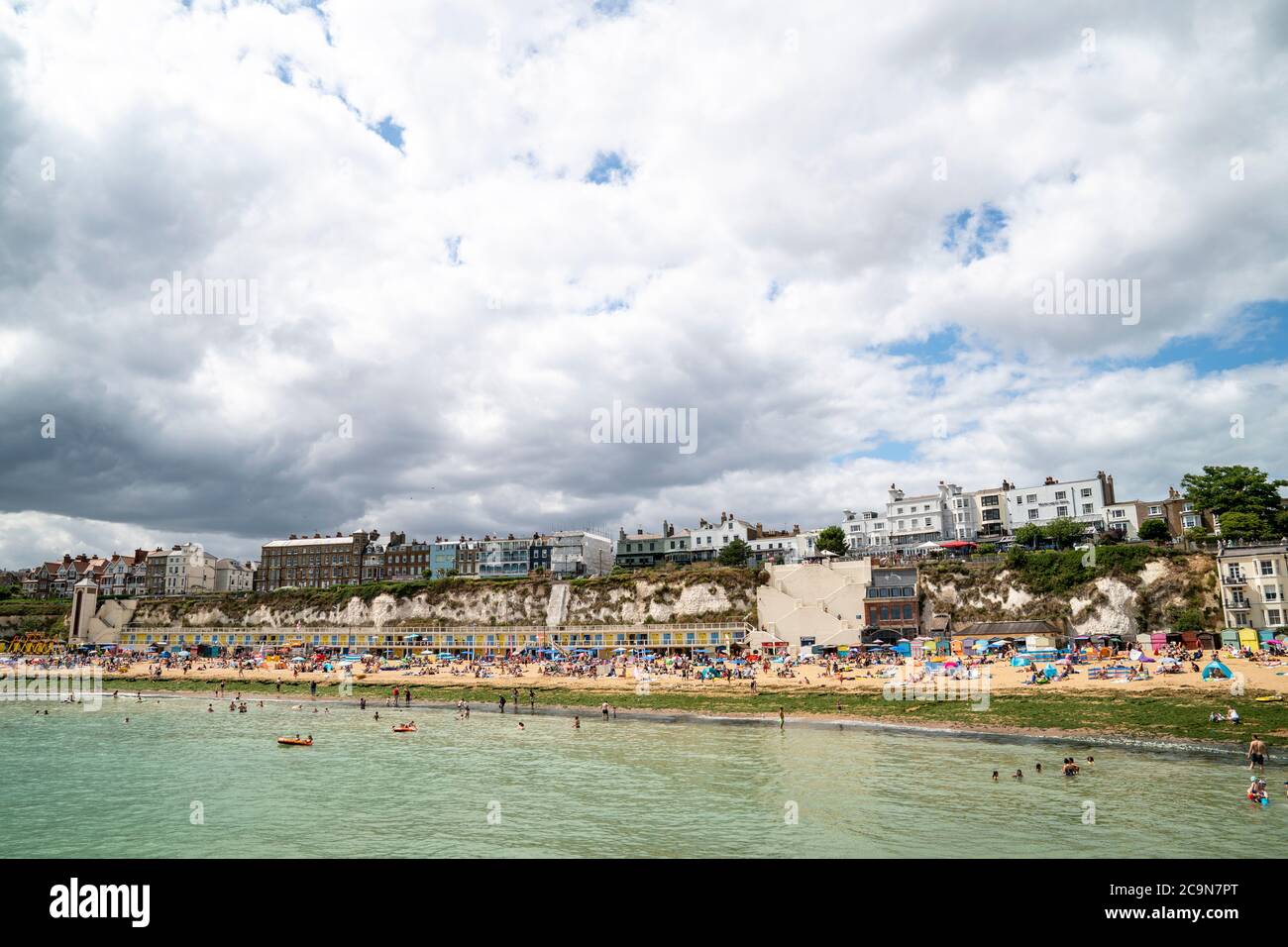 View from the sea of Broadstairs beach crowded with people sunbathing