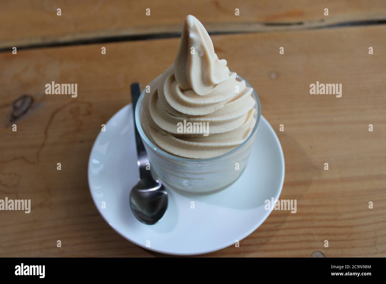 Goat's milk soft serve ice cream in a glass dessert dish, with a silver spoon Stock Photo