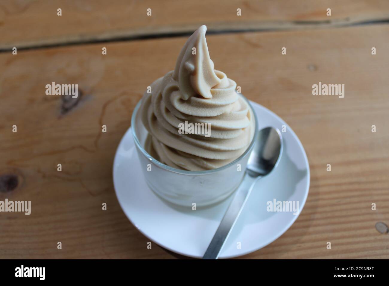 Goat's milk soft serve ice cream in a glass dessert dish, with a silver spoon Stock Photo